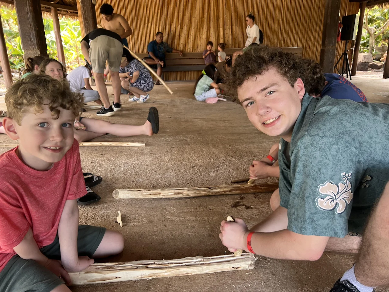 Two young men with wooden tools, trying to create fire.