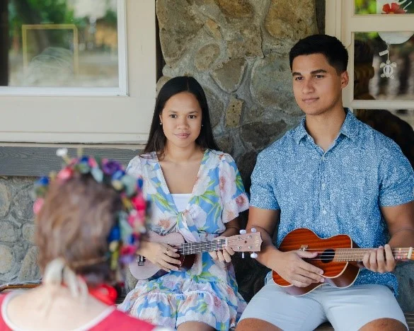 Young man and woman receive a ukulele lesson.