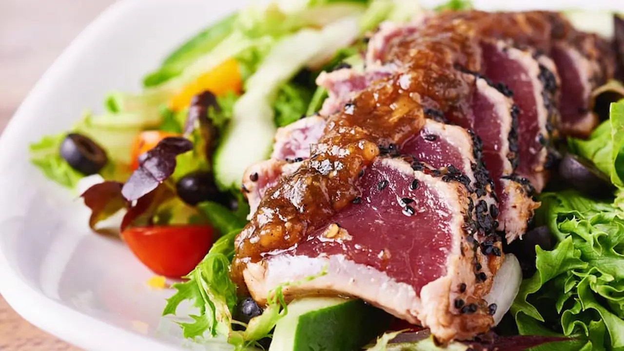 Slices of seared ahi, topped with the brown Kalbi glaze, served on a salad.