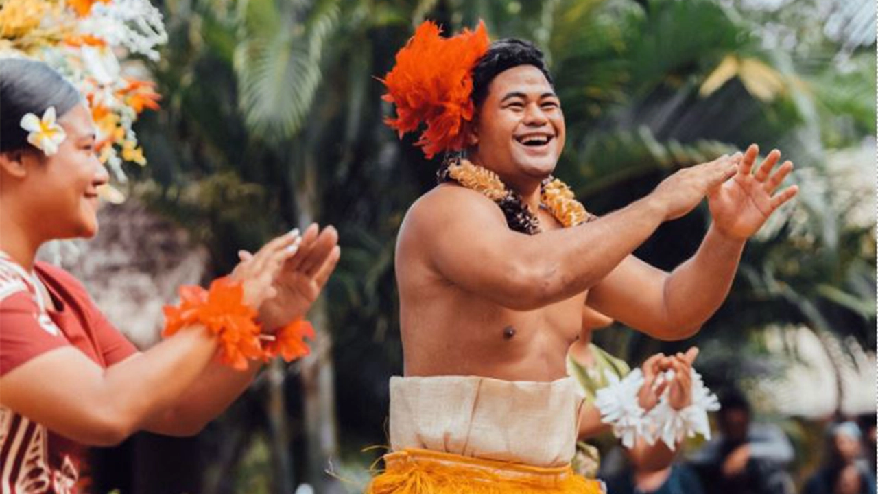 Performers happily performing a Tongan māʻuluʻulu dance on stage at the Polynesian Cultural Center.