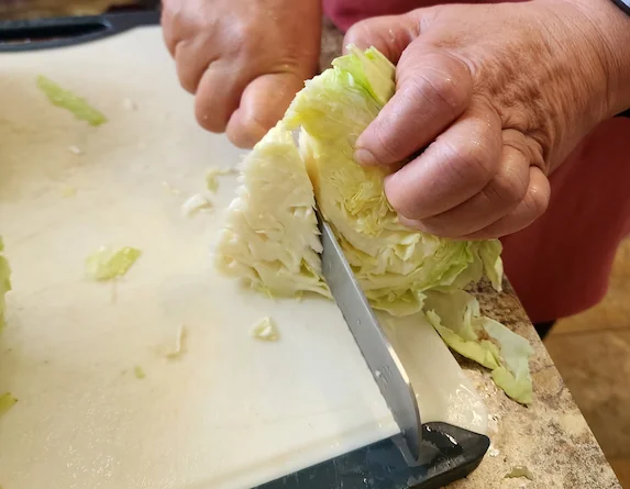 Cutting up the cabbage with a large knife.