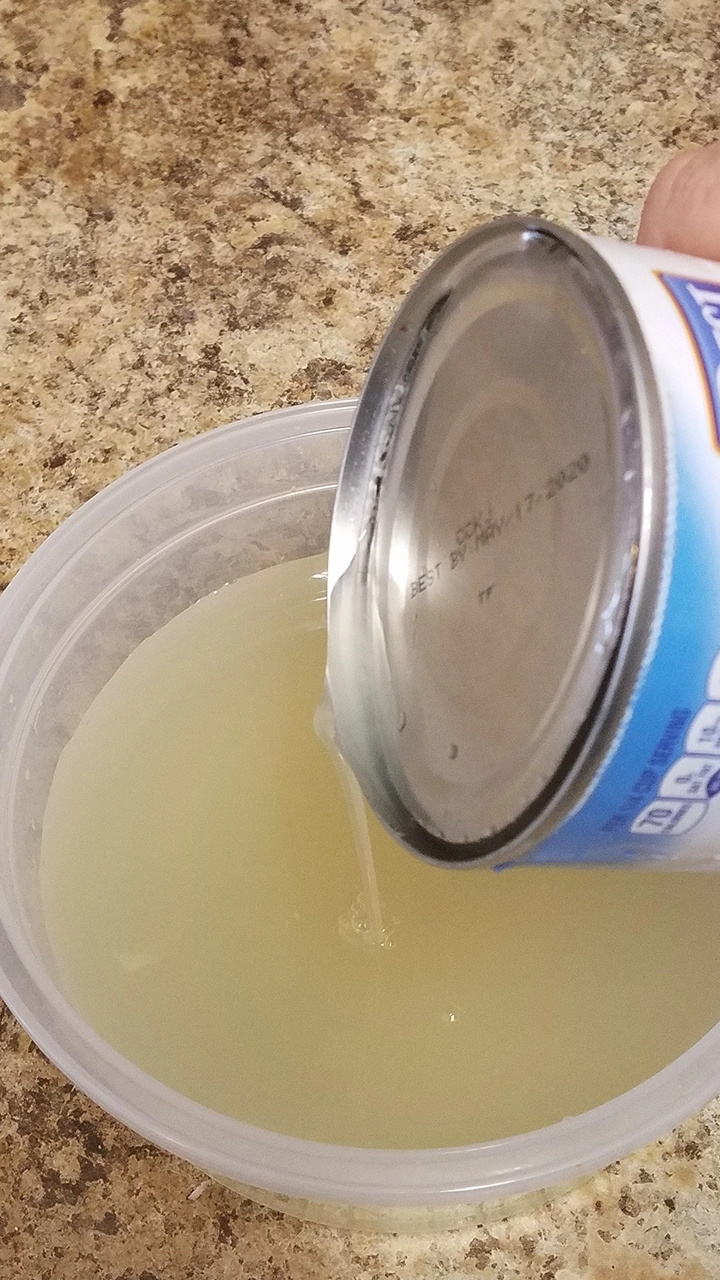 pineapple juice being drained from a can of pineapple