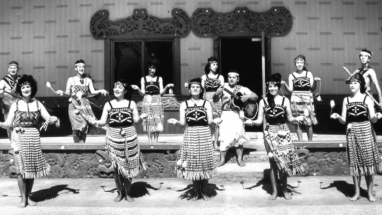 Female performers showcasing the poi in front of a Whare.