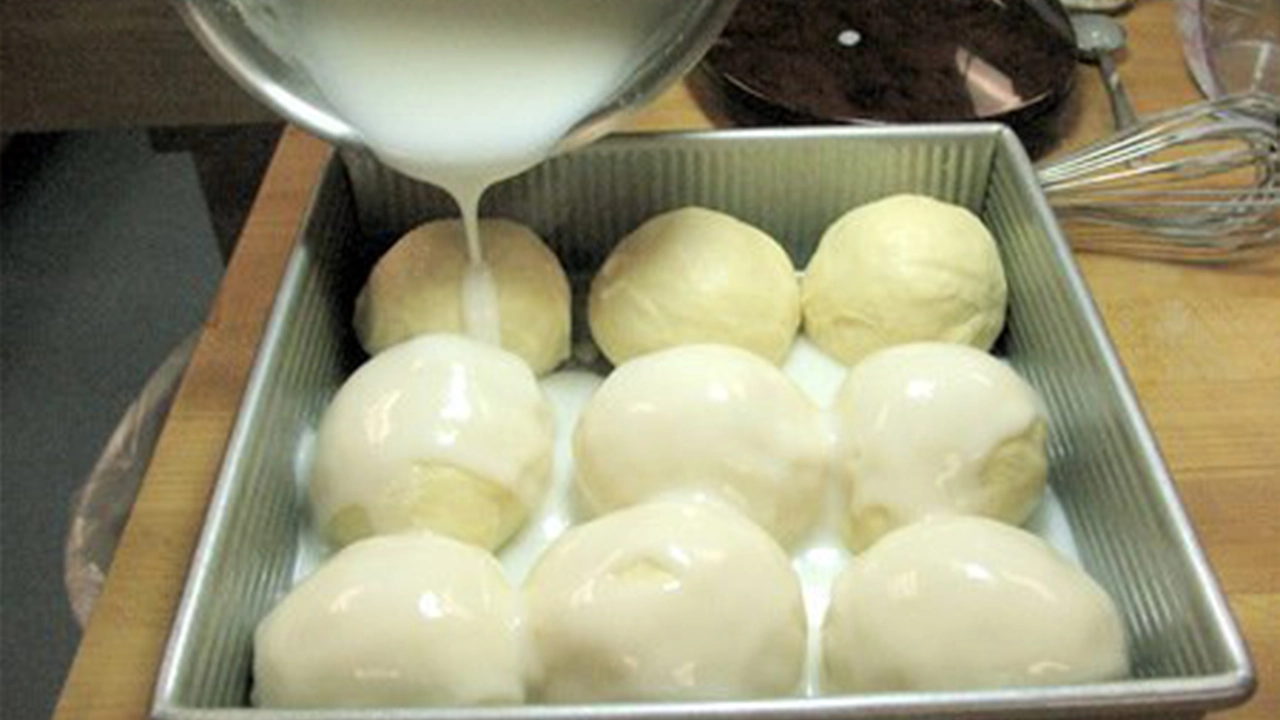 Thickened coconut milk being poured over raised rolls