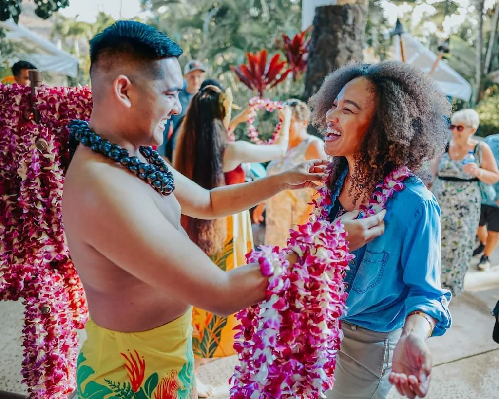 Man giving a happy woman a beautiful purple lei.