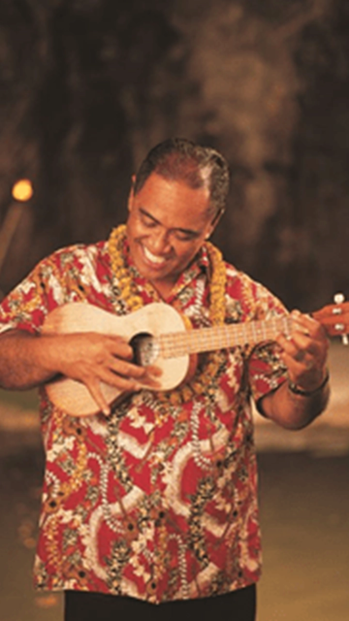 Polynesian man smiling and playing a ukulele