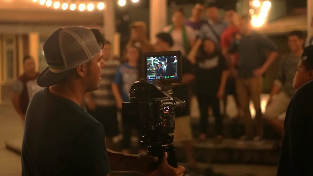 A young man recording video footage at the Hukilau Marketplace.