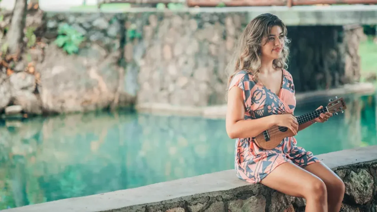 Lady playing an ukulele by the lagoon.