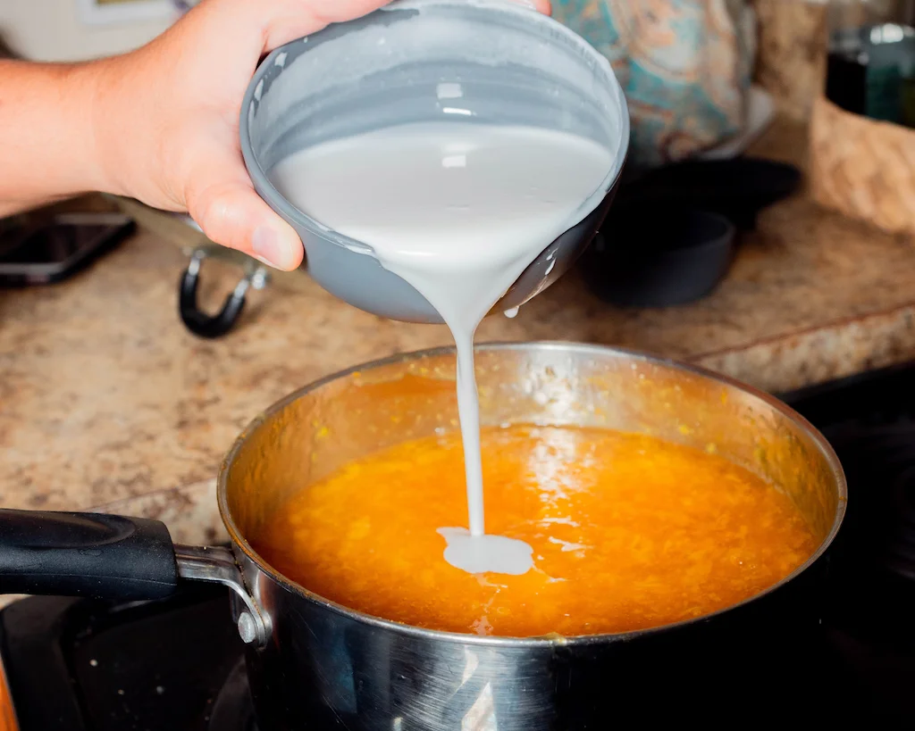 Pouring coconut milk into the supoesi to give that creamy coconut flavor.